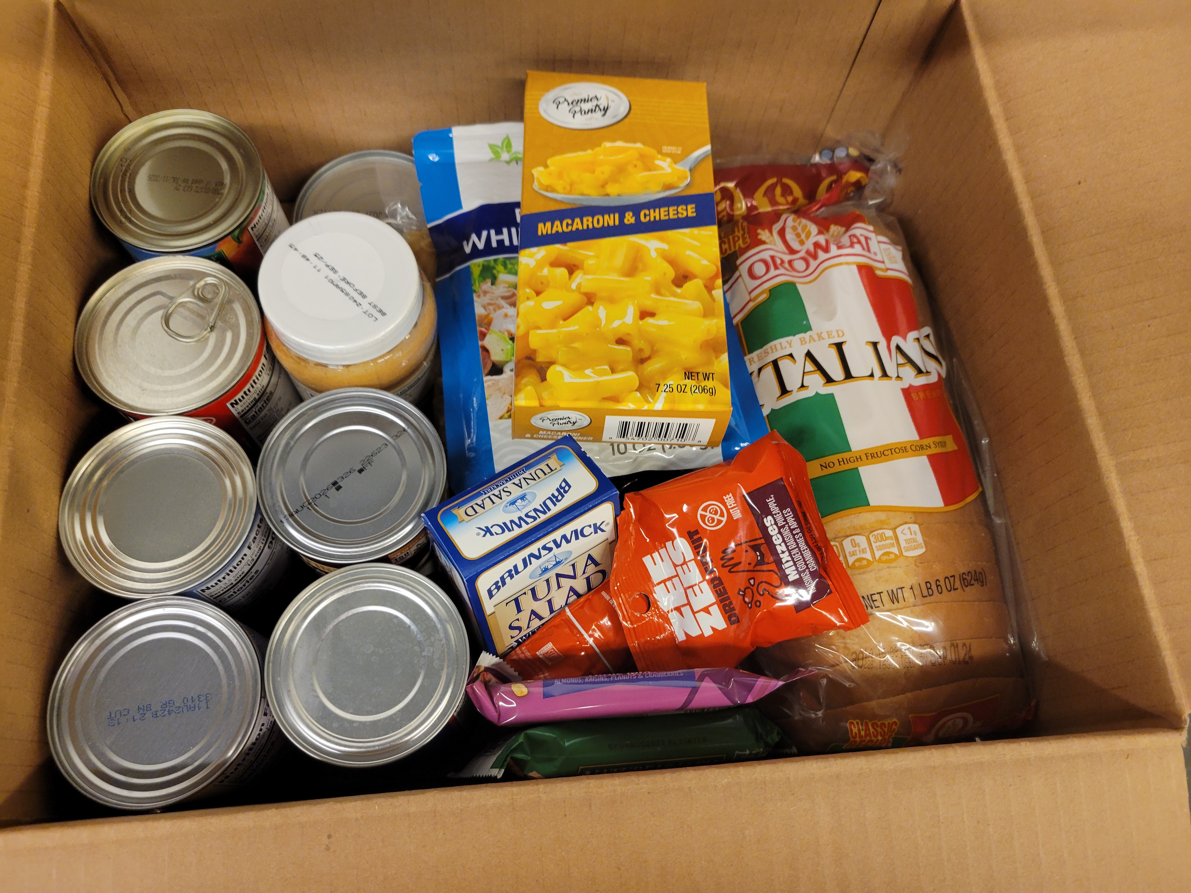 Cardboard box filled with dry goods and bread.